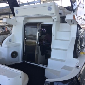 A docked boat with a white exterior, stairs leading to an upper deck, and a glass door opening to the interior.