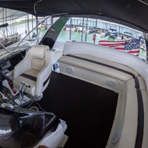 Interior of a covered boat with beige seating, steering wheel, and an American flag at the back.